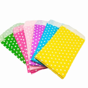 May include: A selection of colourful paper treat bags. Each bag is a different colour, including green, pink, light pink, purple, blue, and yellow. All bags have white polka dots and a scalloped edge.