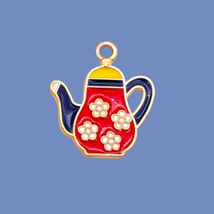 May include: A teapot-shaped charm featuring a red body with white flower patterns, a dark blue handle and spout, and a yellow lid. The charm is outlined in gold-tone metal and includes a small circular loop at the top for attachment purposes.