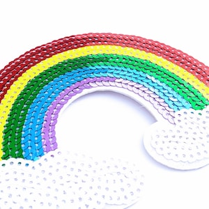 May include: A rainbow-coloured sequin patch with a white cloud design. The rainbow is made of red, orange, yellow, green, blue, indigo, and violet sequins. The cloud is made of white sequins.