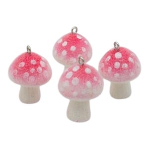 May include: Four small mushroom charms with red caps and white polka dots. Each mushroom has a silver-coloured loop at the top. The stems are a light beige colour. These charms are ideal for jewellery making or other craft projects.