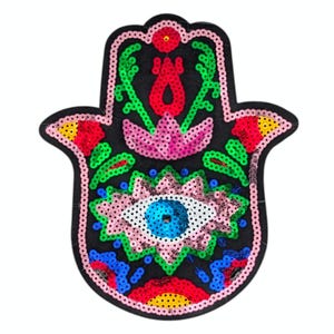May include: Black sequined Hamsa hand patch with a detailed design. The patch features a central eye with a blue iris, surrounded by pink and white sequins. The design includes red, green, and yellow accents, with a pink border.