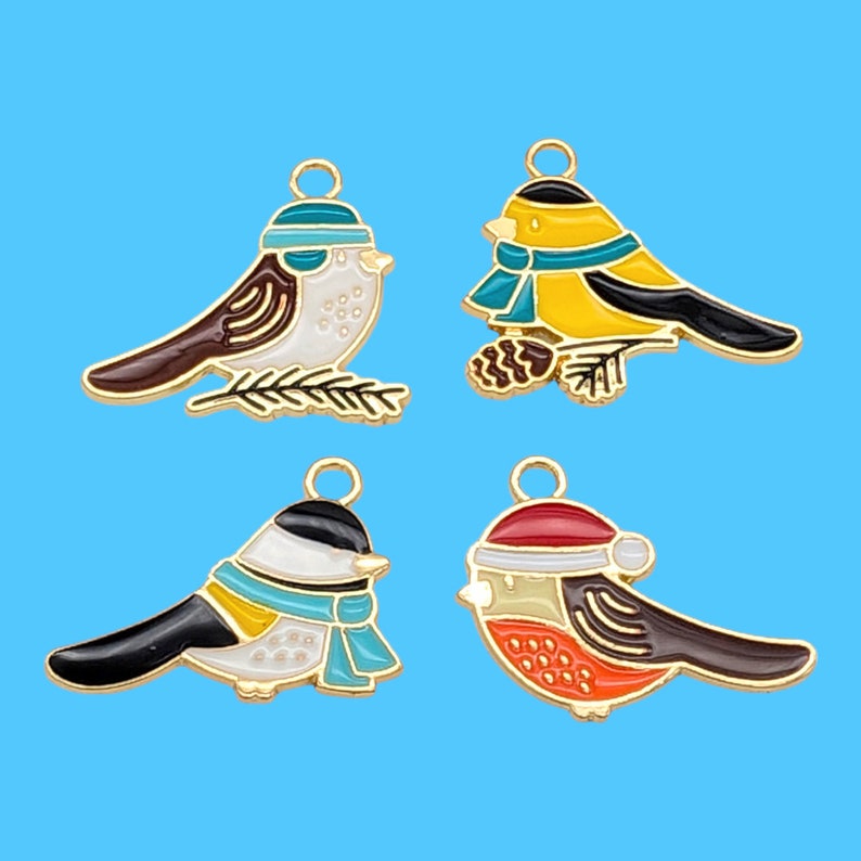 May include: Four gold-tone metal charms featuring different bird designs. Each charm has a loop at the top for attaching to a necklace, bracelet, or other jewelry. The birds are painted in various colors, including blue, red, yellow, and white.