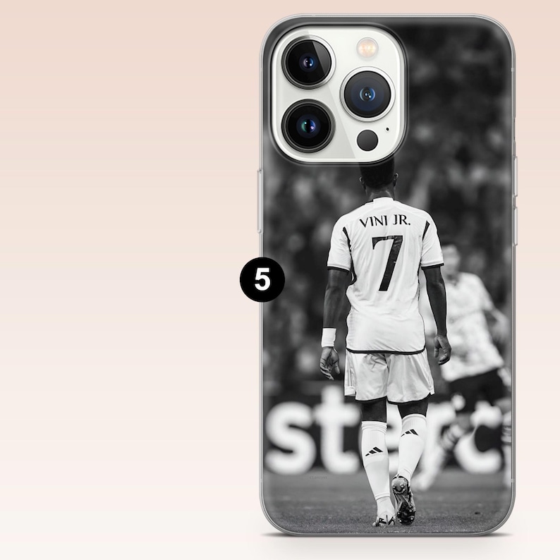 May include: A black and white smartphone case featuring a rear view of a soccer player wearing a jersey with the name VINI JR. and the number 7 printed on the back. The design includes a camera cutout at the top and a small black circle with the number 5.