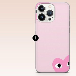 Może przedstawiać: R&oacute;żowe etui na telefon z zabawnym wzorem serca z czarnymi oczami. Etui jest przeznaczone do smartfona i ma gładkie, błyszczące wykończenie. Etui ma przezroczystą obw&oacute;dkę.