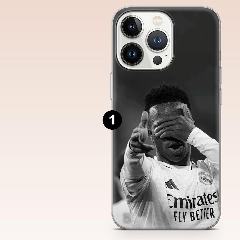 May include: A black and white smartphone case featuring a graphic of a soccer player in a jersey with the text Emirates FLY BETTER. The player is shown with one hand covering their eyes and the other hand pointing forward in a gesture.