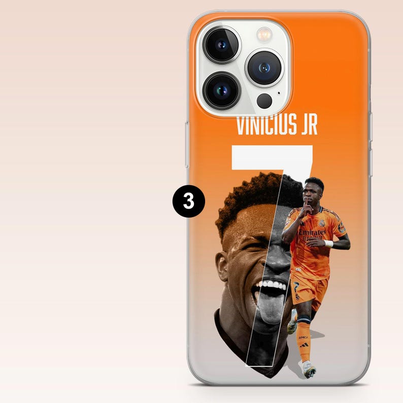 May include: An orange and white smartphone case featuring a large graphic of soccer player Vinicius Jr. with the text VINICIUS JR and the number 7 printed in white. The design includes a close-up portrait and a full-body action shot of the player.