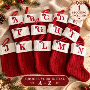 May include: A collection of red knit Christmas stockings featuring white cuffs, each embroidered with a unique letter from A to N in red thread. Each letter is topped with a small Santa hat graphic. A circular tag states 1 STOCKING INCLUDED.