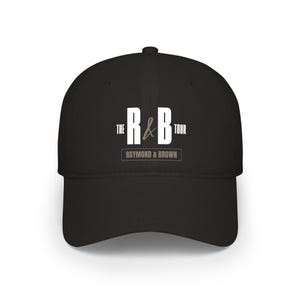 May include: Black baseball cap with a curved brim. The cap features the text "THE R&B TOUR" in white and brown, with "RAYMOND & BROWN" printed below. A stylish accessory for music fans.