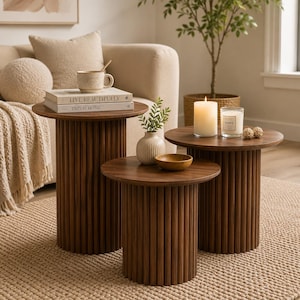 May include: A set of three cylindrical side tables made of dark brown wood with vertical fluted detailing. Each table features a smooth, circular top surface. The tables are arranged in a cluster, varying in height, with a clean, solid construction.