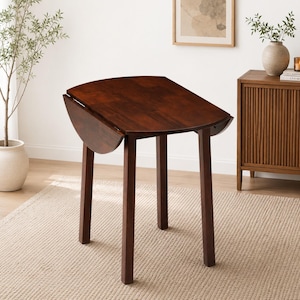 May include: A dark brown wooden drop-leaf table with a rectangular top and rounded edges. The table features four straight legs and two hinged side panels that can be folded down. The wood grain is visible across the surface of the table.