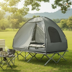 May include: A grey elevated camping tent set on a foldable metal cot frame. The tent features a zipped entrance, a side window, and an interior sleeping pad. A small folding table with camping gear is positioned next to the elevated tent structure.