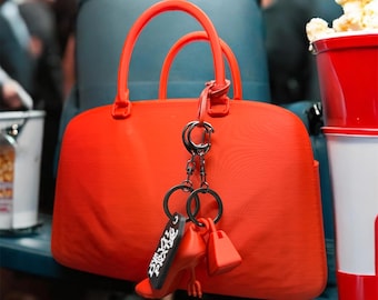 Bolsa e chaveiros em formato de balde de pipoca inspirados em O Diabo Veste Prada 2, impressos em 3D.