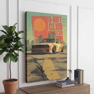 May include: A rectangular wall art print featuring a white E30 car on a cracked asphalt road. The background displays a large orange circle and city skyline silhouettes. The text D-RIFT CLUB E30 is printed in bold orange letters at the top right.