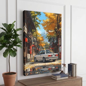 May include: A rectangular wall art print depicting a white saloon car parked on a street lined with traditional buildings and autumn trees with yellow leaves. A mountain is visible in the distance under a blue sky, with a reflection of the car on the ground.