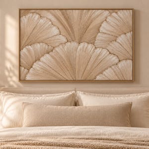 Op de afbeelding: Een rechthoekig wandkunstwerk met een gestructureerd, gelaagd waaiervormig patroon in tinten beige, crème en lichtbruin. Het kunstwerk is ingelijst in een dunne, lichtgekleurde houten lijst en toont een herhalend, organisch, bloembladachtig motief.