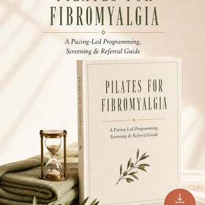 Op de afbeelding: Een boek getiteld Pilates for Fibromyalgia: A Pacing-Led Programming, Screening & Referral Guide met een crèmekleurige kaft, olijfgroene tekst en een illustratie van een olijftak. Daarnaast staan een koperen zandloper en een gevouwen olijfgroene doek.