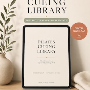 以下が含まれることがあります： インストラクター向けの「PILATES CUEING LIBRARY」を表示するタブレット。画面にはタイトルと260の専門的なキューに関する詳細が表示されます。画像には、緑のある花瓶と「デジタルダウンロード」アイコンが含まれています。