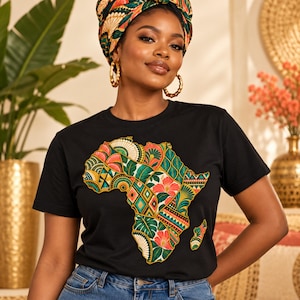 Peut inclure: Un t-shirt noir à manches courtes arborant un grand motif central représentant le continent africain. Le design de la carte est rempli d'un patchwork vibrant et multicolore composé de motifs floraux, géométriques et de feuilles en rouge, vert et or.