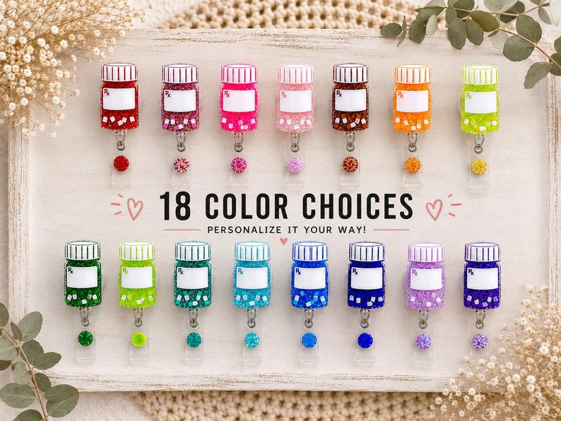 May include: A collection of 18 colorful pill bottle-shaped badge reels. Each reel has a white label and a decorative charm. The text "18 COLOR CHOICES" and "PERSONALIZE IT YOUR WAY!" is displayed on the wooden tray.