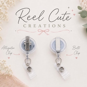 May include: Two clear retractable badge holders with silver clips, labeled "Alligator Clip" and "Belt Clip." The text "Reel Cute Creations" is displayed in elegant script. The background includes floral and fabric elements.