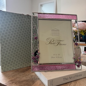 May include: A rectangular silver photo frame featuring textured pink glass panels at the top and bottom. The sides are decorated with metal vines and small purple roses. The insert reads Academy Photo Frame 8 x 10 inches and 20cm x 25cm.