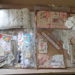 Può includere: Un kit per il fai-da-te in una scatola di cartone contenente pizzo color crema, fiori in tessuto bianco, vari articoli di carta, etichette in stile vintage con testo tra cui 04 JUN 1943 e It's The Little Things In Life, bottoni e un metro a nastro.