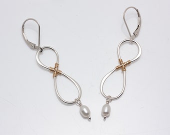 Pendientes colgantes de plata de ley con forma de aro infinito y perlas ovaladas de agua dulce.