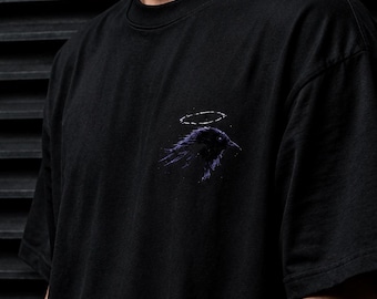Camiseta gráfica Dark Raven, estilo gótico urbano, diseño minimalista morado, camiseta unisex de algodón.