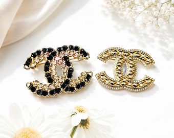 Par de broches vintage Chanel CC. Esmalte negro, cristal y tono dorado.