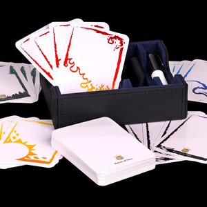 May include: A black leatherette card storage box with blue interior lining, containing a dry erase marker. The set includes multiple white cards with colorful decorative borders in red, yellow, blue, green, and purple, featuring the text Baron of Dice.