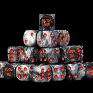 May include: A pyramid stack of marbled black and white dice with bright orange pips. Several dice feature the text FUCK ME in orange lettering on one face. The dice have a glossy finish and are arranged in a triangular formation against a black background.
