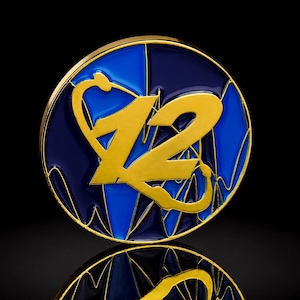 Könnte beinhalten: Eine kreisförmige Anstecknadel aus Metall mit goldenem Rand, einem glänzenden Hintergrund aus blauem und dunkelblauem Emaille und einer stilisierten goldenen Zahl 12. Das Design zeigt ein goldenes Stethoskop, das in die Zahl integriert ist.