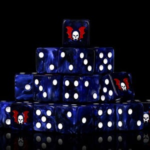 May include: A pyramid-shaped stack of dark blue marbled dice with white pips. Several dice feature a custom graphic of a white skull with red bat wings on one face. The dice are arranged in a tiered formation against a solid black background.