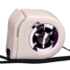 May include: A white retractable measuring tape with a rounded, compact plastic casing. The centre features a circular emblem with a purple and white geometric pattern and a black star-like design. A black lanyard is attached to the side.