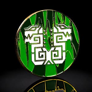 Può includere: Una spilla metallica circolare con uno sfondo in smalto verde brillante e una grafica bianca stilizzata di due creature simili a draghi specchiate. Il design è incorniciato da un sottile bordo in metallo color oro con finitura lucida.