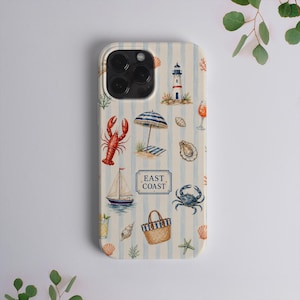 May include: A phone case with a light blue and white vertical striped background featuring watercolor illustrations of a lighthouse, lobster, sailboat, beach umbrella, crab, and a straw tote bag. The text EAST COAST is centered in a blue frame.