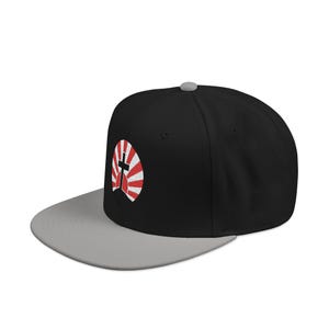 May include: Black and gray baseball cap with a flat brim. The cap features a red and white cross design on the side. The cap has a gray brim and a black crown.