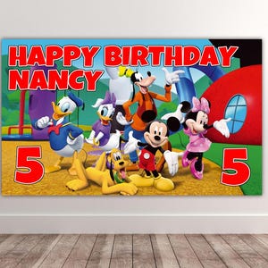 May include: A rectangular birthday banner featuring the text HAPPY BIRTHDAY NANCY and the number 5 on both sides. The design displays Mickey Mouse, Minnie Mouse, Donald Duck, Daisy Duck, Goofy, and Pluto in a colorful park setting.