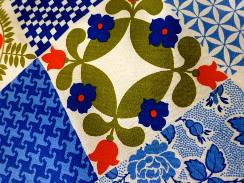 May include: Close-up of a fabric with a patchwork design. The fabric features various geometric and floral patterns in blue, red, green, and white. The patterns include stylized flowers, geometric shapes, and floral motifs, creating a vibrant and colorful textile.