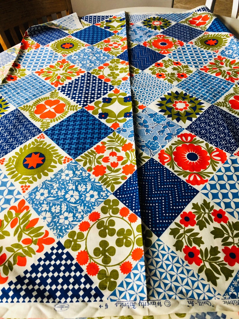 May include: A colorful fabric with a patchwork design. The fabric features a variety of geometric and floral patterns in shades of blue, orange, green, and white. The fabric is labeled "Waverly Fabrics".