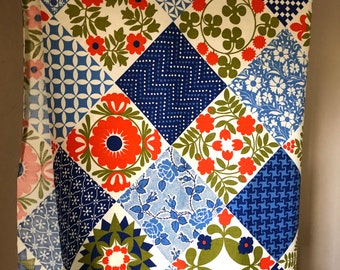 May include: A vintage fabric with a patchwork design. The fabric features a variety of geometric and floral patterns in shades of blue, red, green, and white. The fabric is labeled "Protected with Scotchgard".