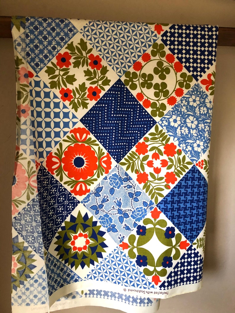May include: A vintage fabric with a patchwork design. The fabric features a variety of geometric and floral patterns in shades of blue, red, green, and white. The fabric is labeled "Protected with Scotchgard".