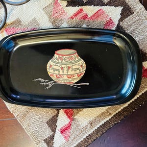 May include: Black rectangular serving tray with a decorative Native American pottery design. The pottery is beige, red, and green, with a black background. The tray has a glossy finish and a raised edge.