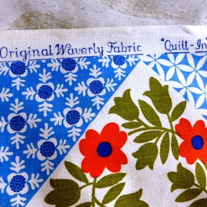 May include: Close-up of a fabric swatch with a floral and geometric pattern. The fabric features red flowers with blue centers, green leaves, and blue and white geometric shapes. The text "An Original Waverly Fabric" and "Quilt-In" is printed on the fabric.