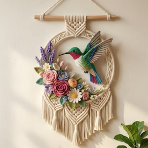 May include: A macrame wall hanging featuring a crocheted hummingbird with green, red, and blue feathers. The bird is positioned within a circular frame adorned with crocheted flowers in shades of pink, purple, yellow, and white, finished with fringe.
