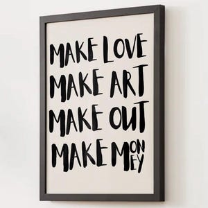 以下が含まれることがあります： 「MAKE LOVE MAKE ART MAKE OUT MAKE MONEY」という言葉が黒い太字でオフホワイトの背景に書かれた額入りのアートプリント。フレームはシンプルな黒い長方形で、アートワークは白い壁に飾られています。