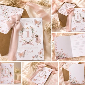 May include: A first birthday greeting card for a daughter featuring a floral wreath, the number one, a fairy illustration, and butterflies. The card is adorned with a soft pink organza ribbon and includes a matching envelope with a floral interior liner.