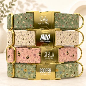 May include: A stack of four fabric pet collars featuring floral and bee patterns in green, cream, and pink. Each collar has a gold-tone metal buckle engraved with a name and the phone number 123-456-7890, including Lily, Milo, Stella, and Cooper.