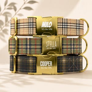May include: Three pet collars stacked vertically, each featuring a gold-tone metal buckle engraved with names and phone numbers. The top collar is beige plaid, the middle is green plaid, and the bottom is dark navy plaid, all with gold hardware.