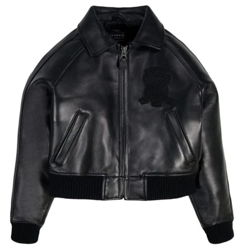 May include: A black leather bomber jacket featuring a classic collar, a full-length front zipper closure, and two slanted welt pockets. The jacket includes black ribbed knit cuffs and a matching ribbed hem, with a tonal embroidered patch on the chest.